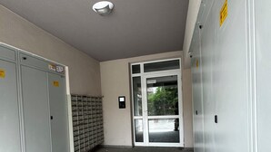 Un couloir avec des casiers, un détecteur d’incendie et une porte donnant sur l’extérieur.