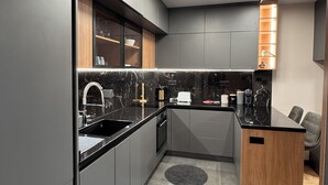 Une cuisine moderne avec des meubles de rangement aux couleurs sombres, un plan de travail noir et un four encastré.