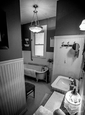 Une salle de bain de style ancien avec une baignoire sur pieds, un lavabo et un miroir.