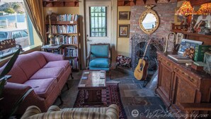 Ein gemütliches Wohnzimmer mit Kamin, Bücherregalen, einer Couch und einer Gitarre.
