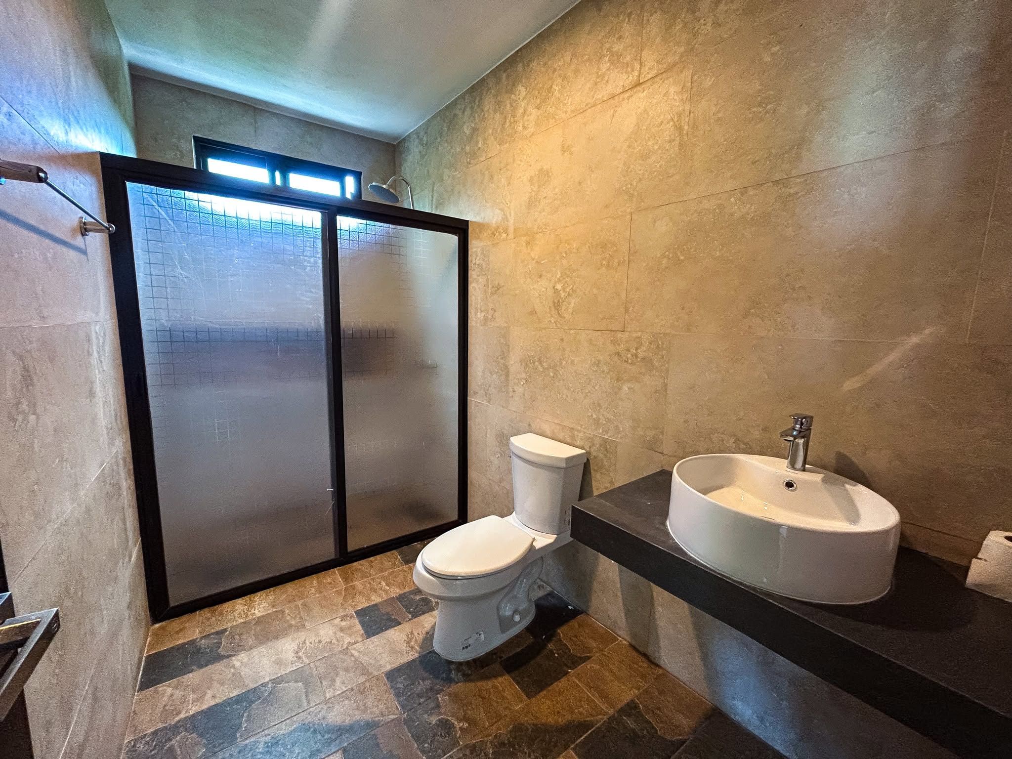 A modern bathroom with a toilet, a sink, and a glass shower enclosure.