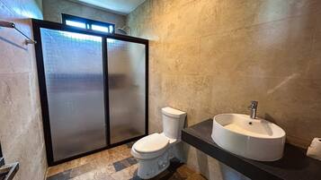 A modern bathroom with a toilet, a sink, and a glass shower enclosure.