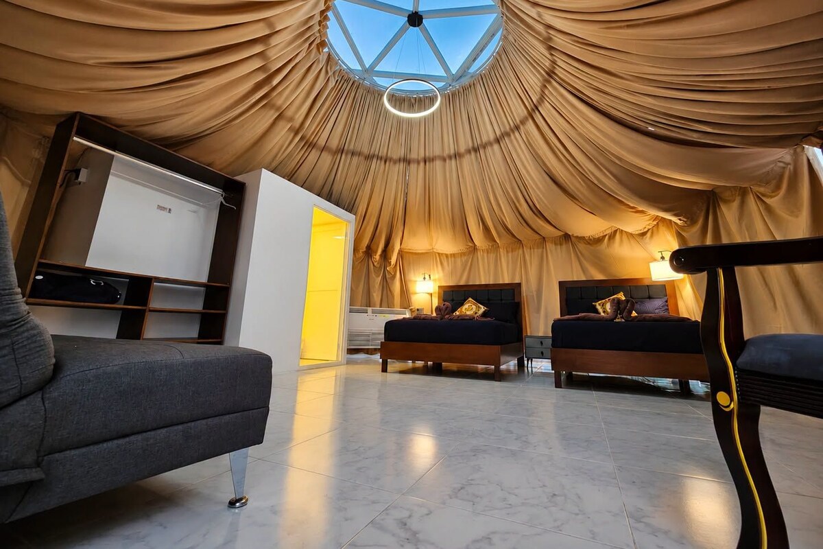 A bedroom with a vaulted ceiling, two beds, a desk, and a chair.