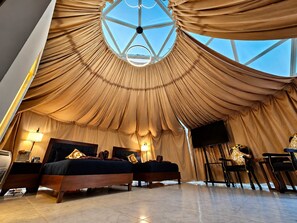 Une chambre avec deux lits, une télévision et une grande fenêtre circulaire.