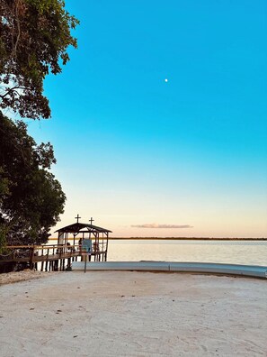 Une plage avec une structure en bois, peut-être un kiosque, près de l’eau.