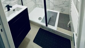 Een moderne badkamer met een douchecabine van glas, een wit wastafelmeubel en een zwarte mat.