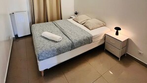 Een keurig opgemaakt slaapkamer met een bed, een nachtkastje met lamp en een radiator.