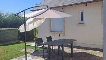 Un patio exterior con mesa y sillas, un paraguas grande y una chimenea.