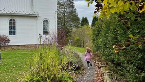 A white church with a pointed steeple and a gravel path leading to it.
