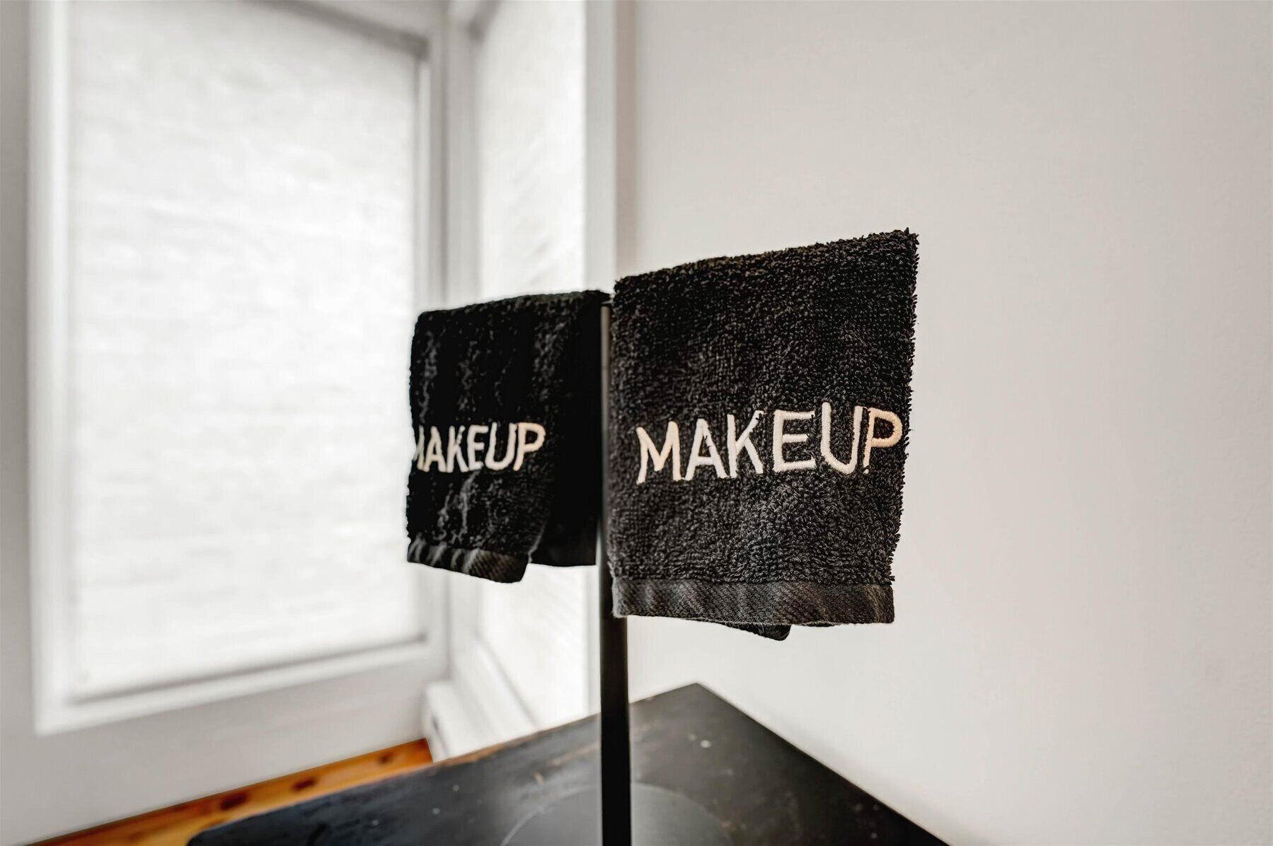 Dos toallas negras con la palabra 'MAKEUP' en un soporte.