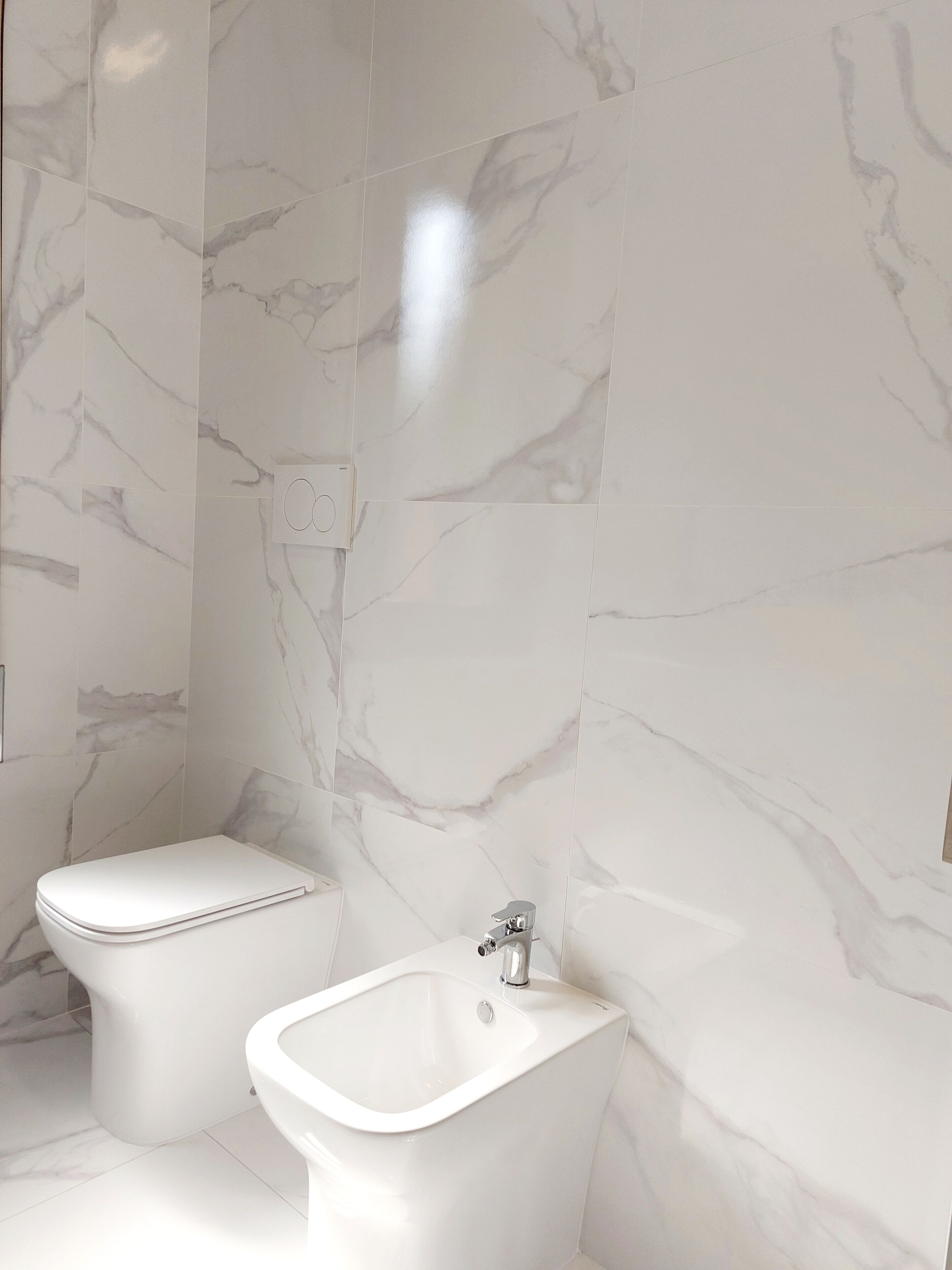 Une salle de bain avec des toilettes, un bidet et un lavabo, le tout de couleur blanche.