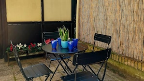 A patio with a round table, two chairs, a potted plant, and a bamboo fence. - Al Pettirosso: 15 min to Venice, 2 Double Bedrooms, Free Private Parking (Venezia)