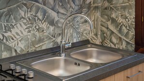 A kitchen with a double sink, a gas stove, and wooden cabinets. - Al Pettirosso: 15 min to Venice, 2 Double Bedrooms, Free Private Parking (Venezia)