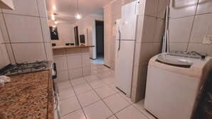 A kitchen with a gas stove, a refrigerator, and a countertop. - Flat Atlantic Ocean - Praia de Iracema (Fortaleza)