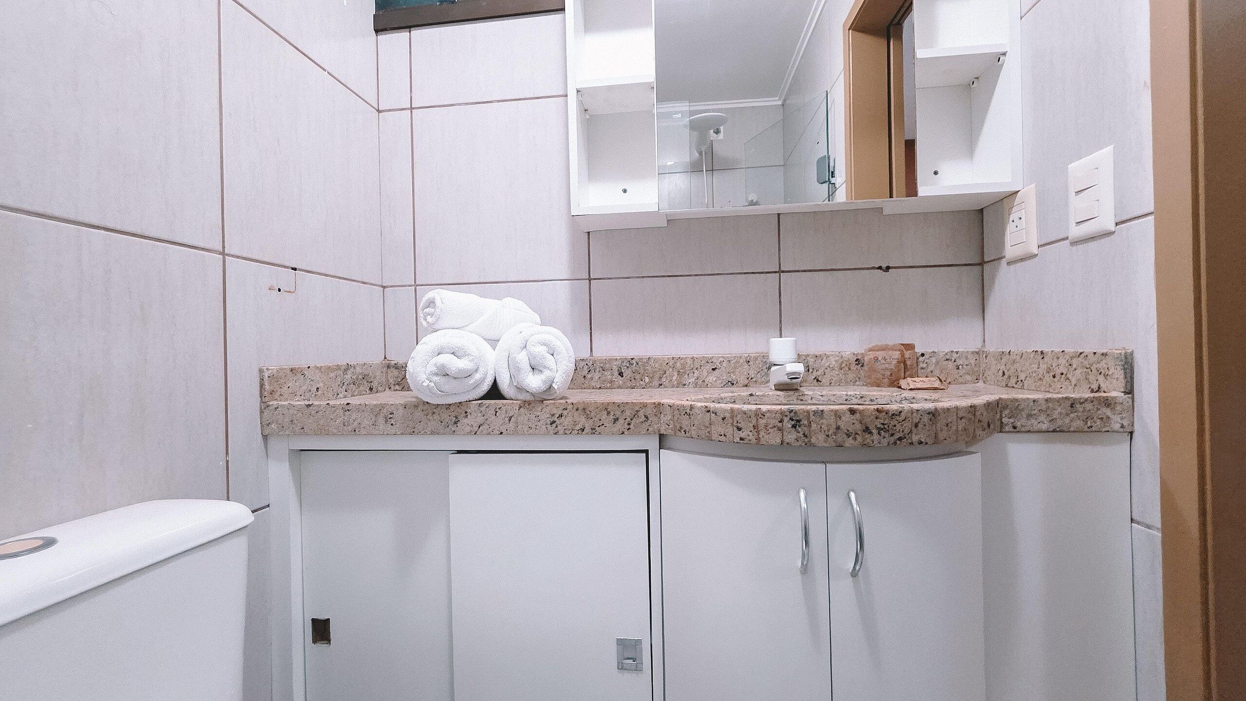 A bathroom with a granite countertop, a sink, a mirror, and a towel rack.