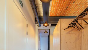 A hallway with a white door, a wooden wall, and a hanging light fixture. - La Camuche by Hélène Dutrieu (Tournai)