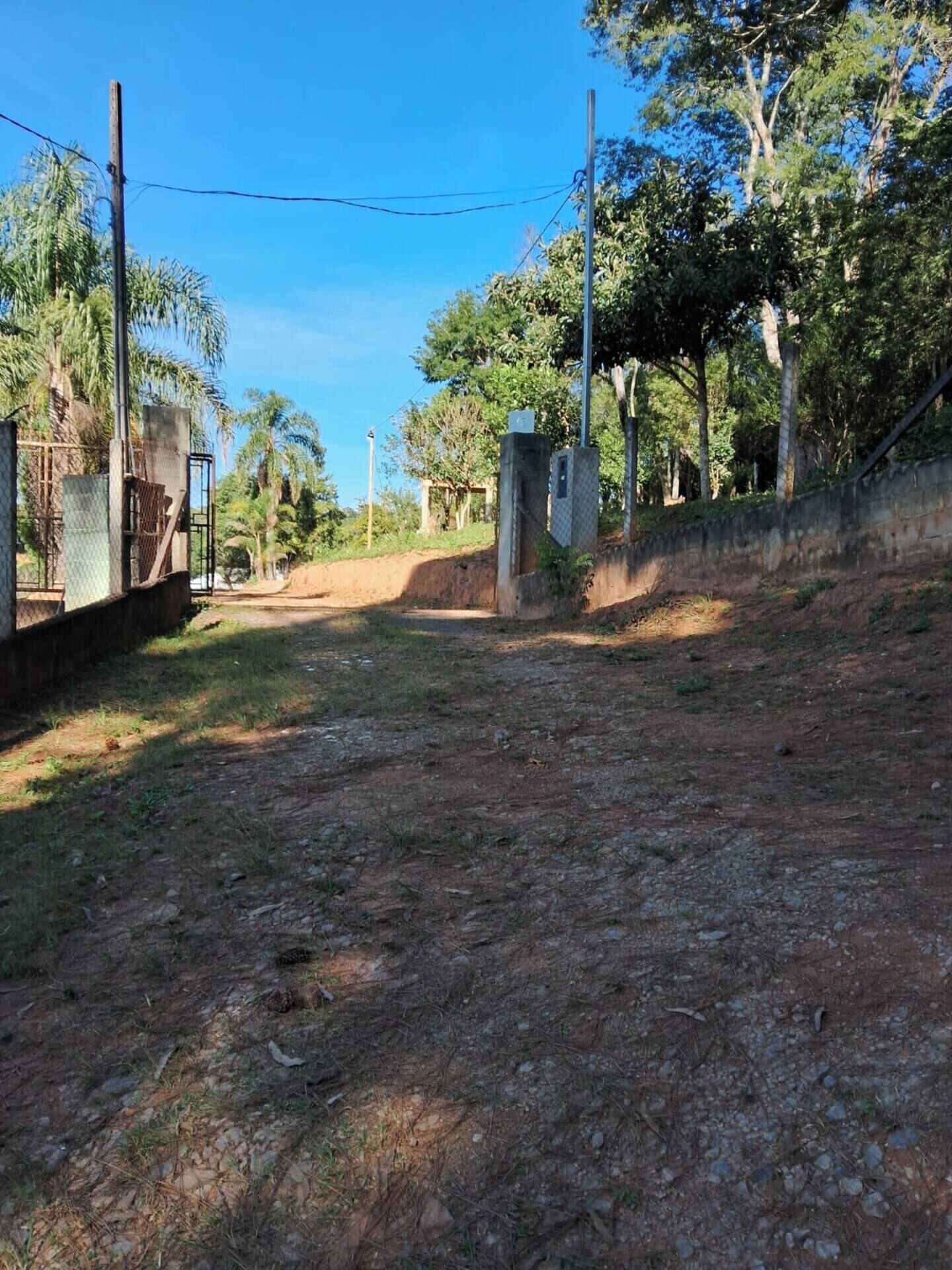 A dirt road leading to a gated area with a fence and utility poles.