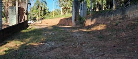 A dirt road leading to a gated area with a fence and utility poles.