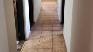 Un corridoio con pavimento piastrellato e soffitto in legno.