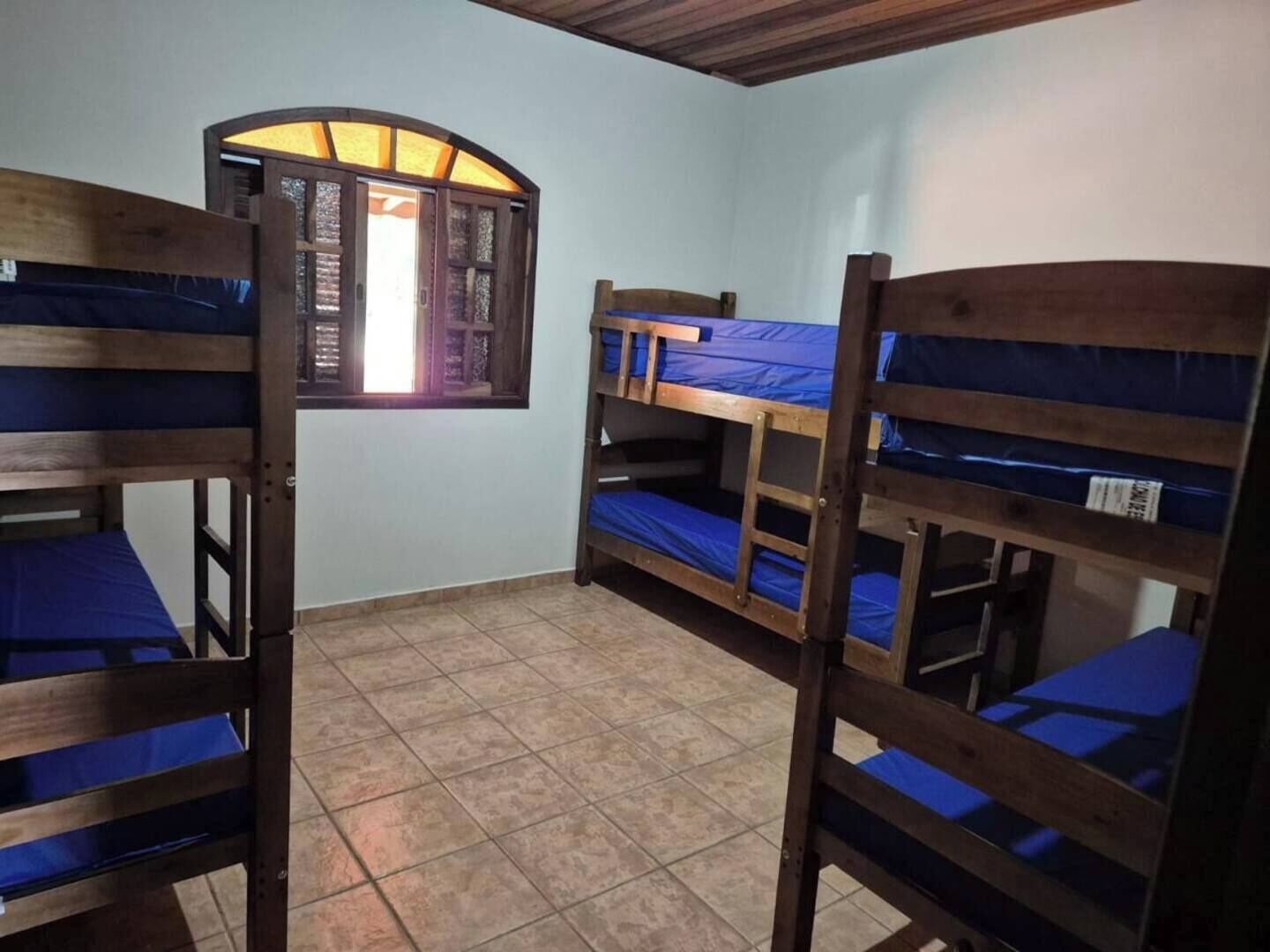 Un dormitorio con literas, una ventana con vistas y suelo de baldosas.
