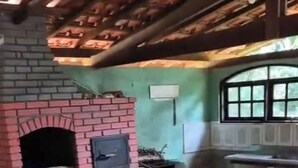 Un camino in mattoni con una TV montata sopra, una finestra e un tavolo con sedie in una stanza con pavimento piastrellato.