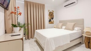 Una habitación de hotel moderna con una cama grande, un escritorio, un televisor y un aire acondicionado.