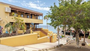 Un edificio amarillo con balcón, un cartel que dice 'Doctor' y vista a la playa.