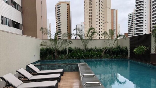 A swimming pool with lounge chairs and a wooden deck. - Compacto de luxo - One Milênio Cocô (Fortaleza)