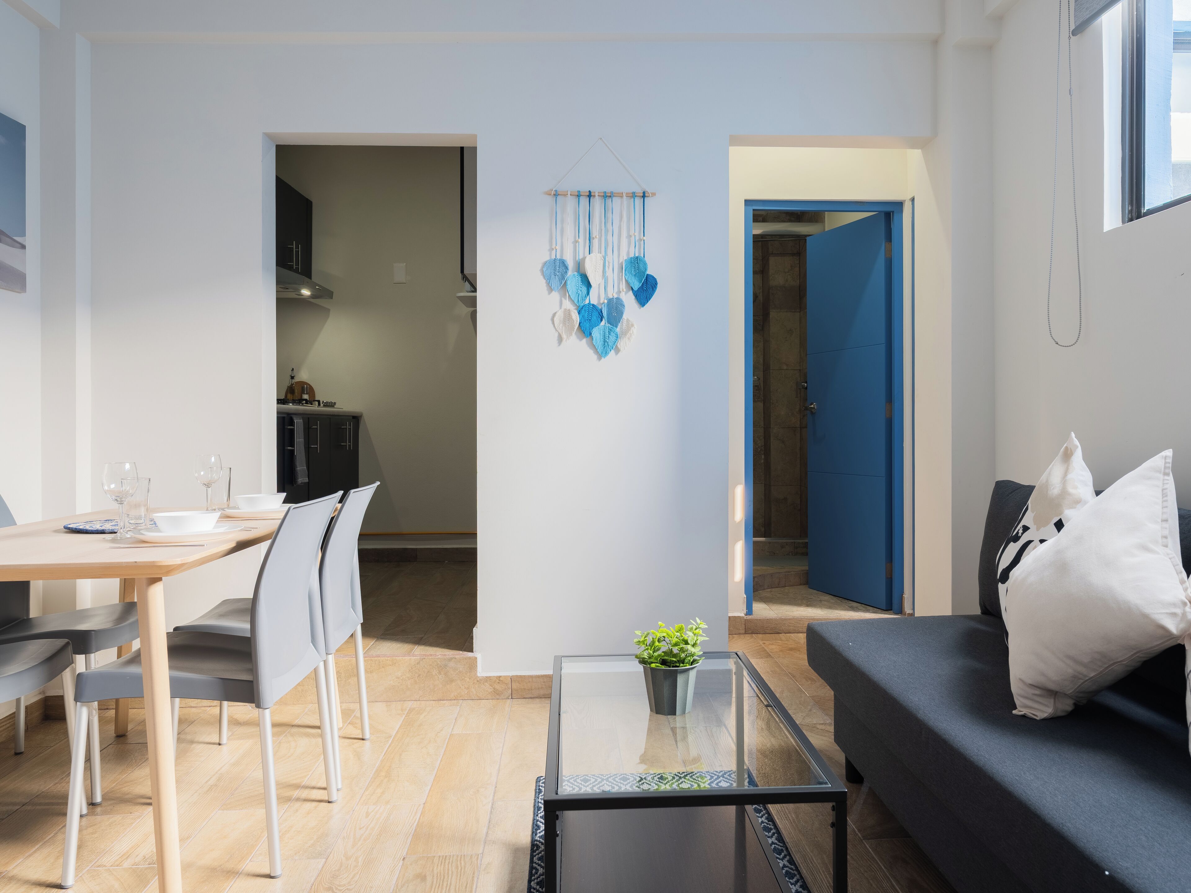 A modern living room with a glass coffee table, a sofa with a pillow, and a dining area with chairs and a table.