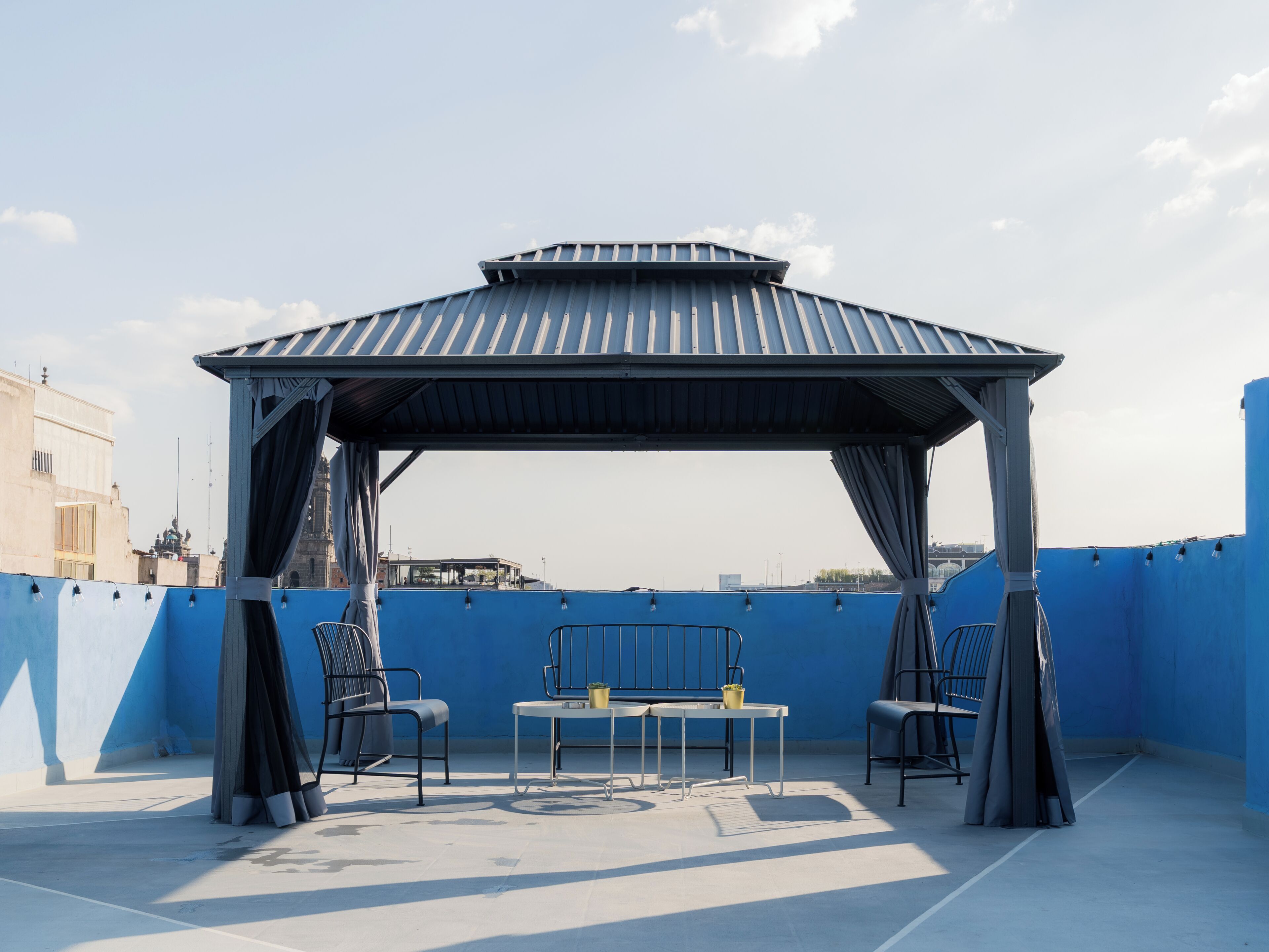 Een terras op het dak met een overdekte zithoek, een tafel en stoelen.