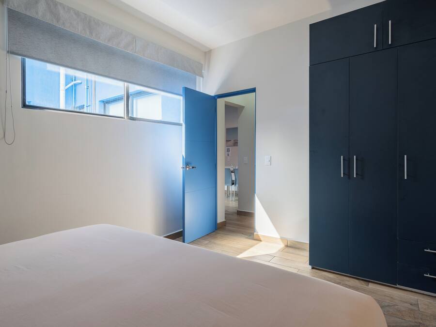 A bedroom with a bed, a wardrobe, and a window.