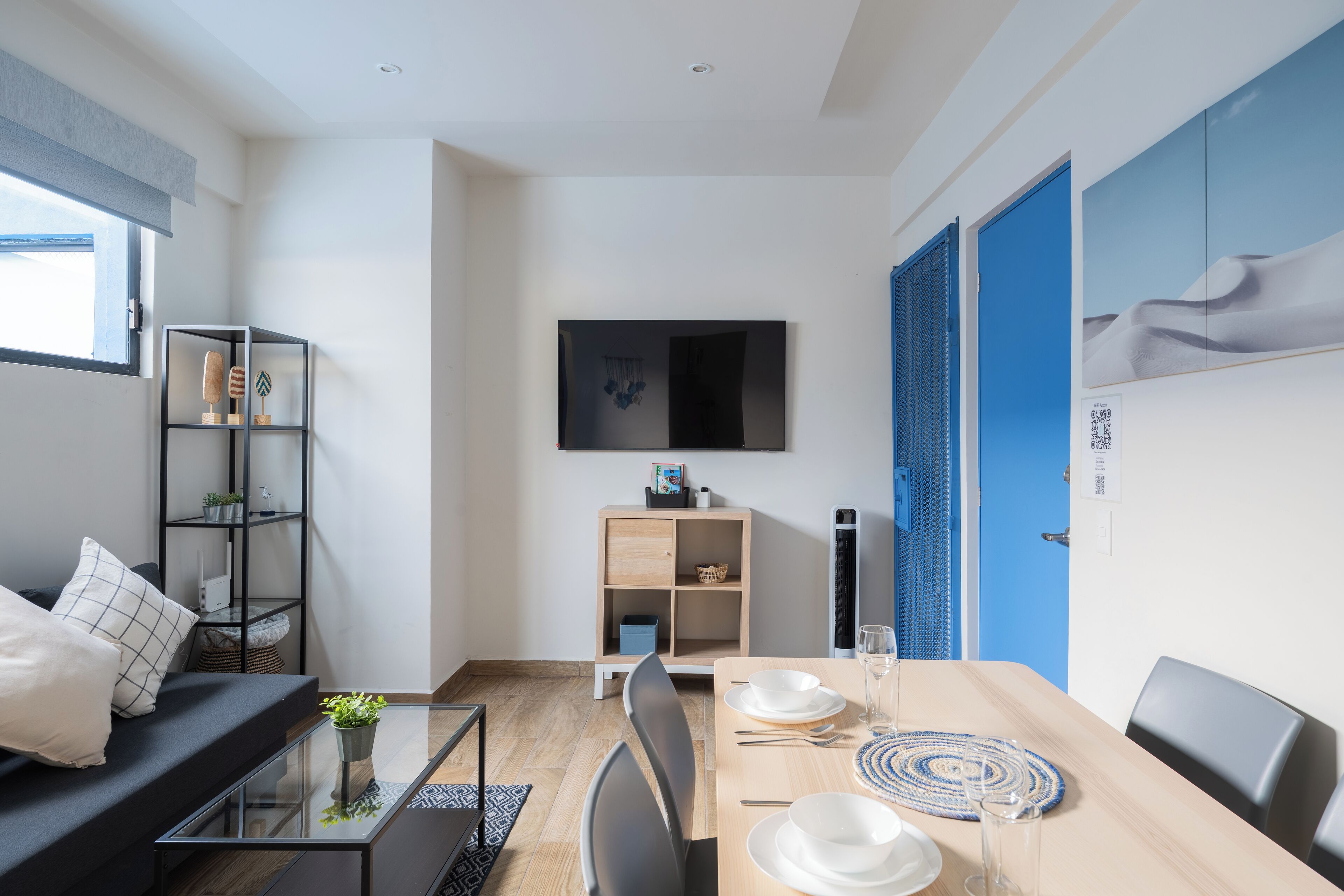 A modern living room with a sofa, coffee table, and TV mounted on the wall.