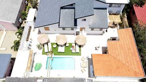 Vue aérienne d’une propriété résidentielle dotée d’une piscine, d’un espace salon extérieur et d’un jardin.