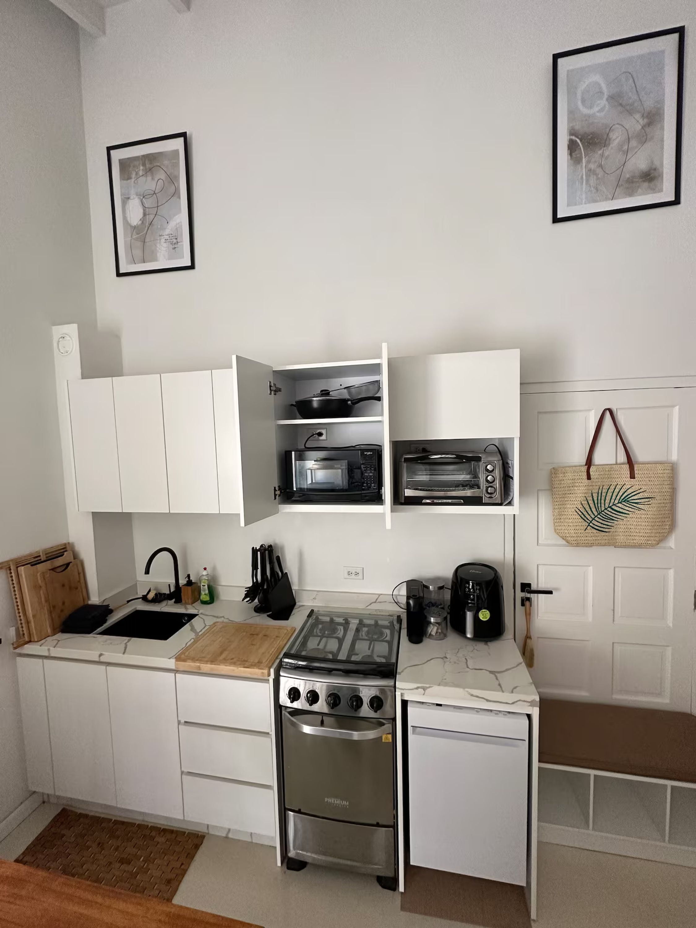 A compact kitchen with white cabinets, a gas stove, a microwave, and a toaster.