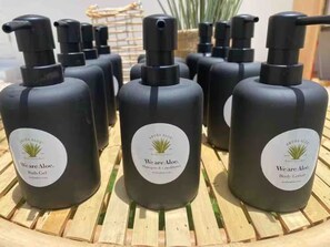 Presentación de geles de ducha Weare Aloe en botellas negras con etiquetas blancas, sobre una superficie de madera.