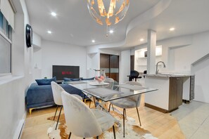 A modern living room with a glass dining table, sofas, and a TV displaying 'NETFLIX'. - Downtown Montreal 3 Floor apartment (montreal)