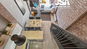 Un intérieur moderne comprenant un coin repas, un escalier et un mur en briques.