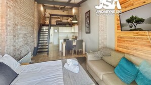 Une chambre d’hôtel confortable, dotée d’un lit, d’un canapé, d’un coin repas et d’un escalier menant à une mezzanine.
