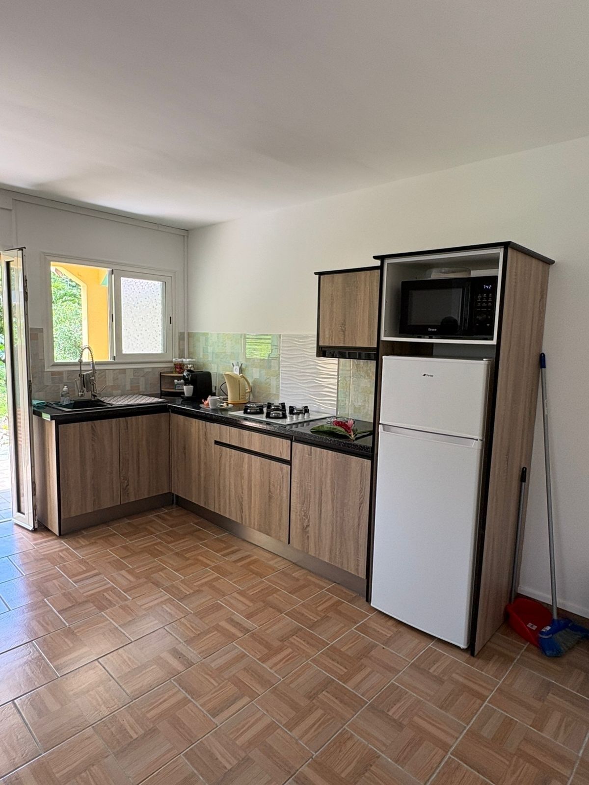 Uma cozinha compacta com armários de madeira, geladeira branca, micro-ondas e pia.