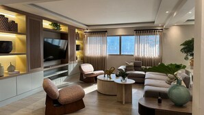 Un salon moderne comprenant un canapé, des fauteuils, une table basse et un téléviseur.