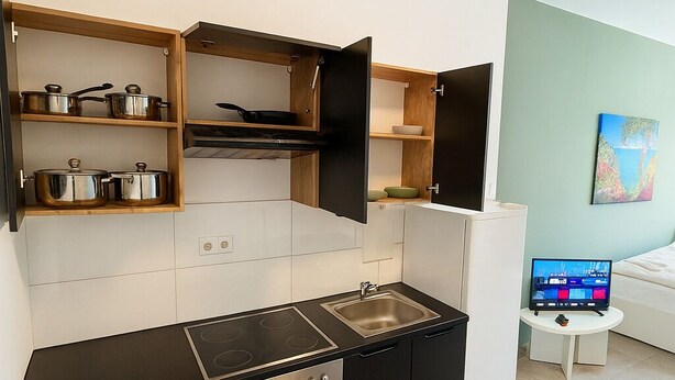Uma cozinha moderna com eletrodomésticos embutidos, uma área de refeições com televisão e um quadro na parede.