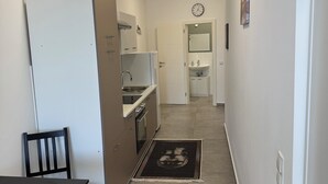 A narrow hallway with a kitchen area, a dining table, and a chair. - City apartment no. 1 with comfort (Pforzheim)