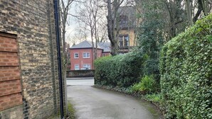 A narrow paved alleyway flanked by brick buildings and dense foliage. - Sefton Park n Princes Park and Lark Lane the other end of Linnet and bus to LFC (Liverpool)
