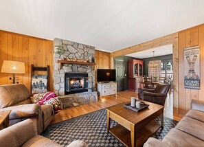 A cozy living room with a stone fireplace, leather sofas, a wooden coffee table, and a television.