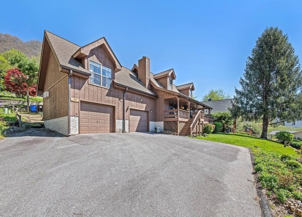 A two-story house with a large garage, a covered porch, and a driveway.