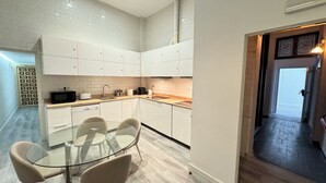 Une cuisine moderne avec des meubles blancs, une table à manger en verre et un plan de travail en bois.