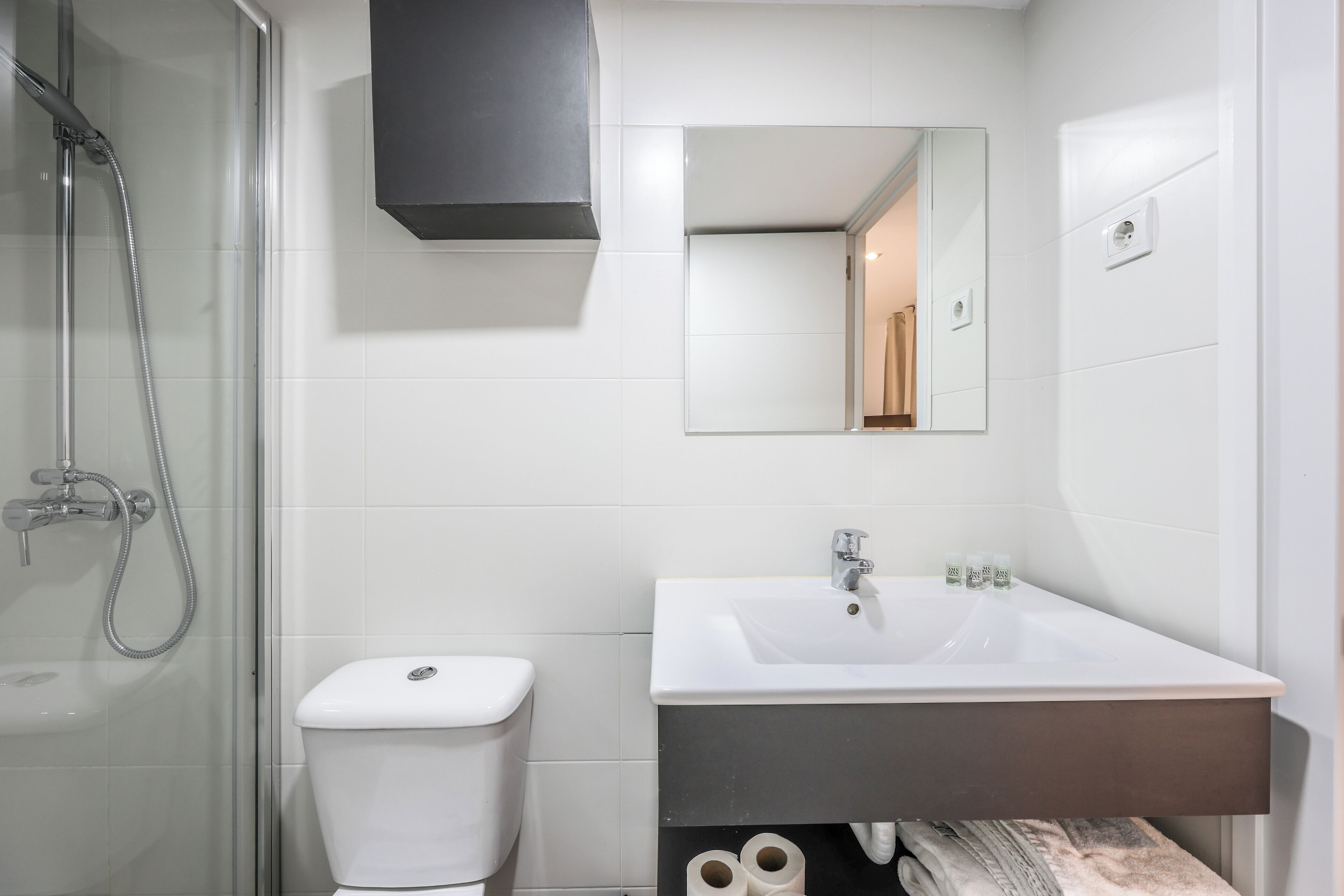 A bathroom with a shower, toilet, sink, and mirror.