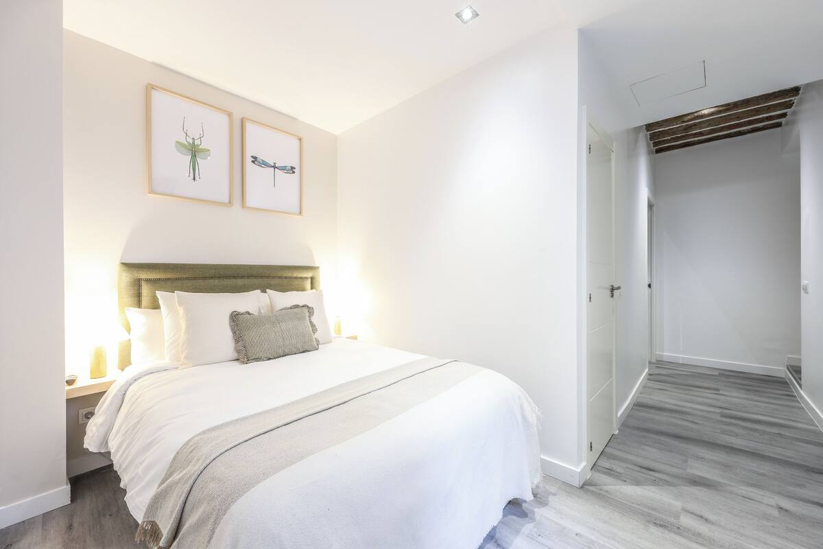 Une chambre à coucher moderne avec un grand lit, une tête de lit et deux tableaux encadrés accrochés au mur.