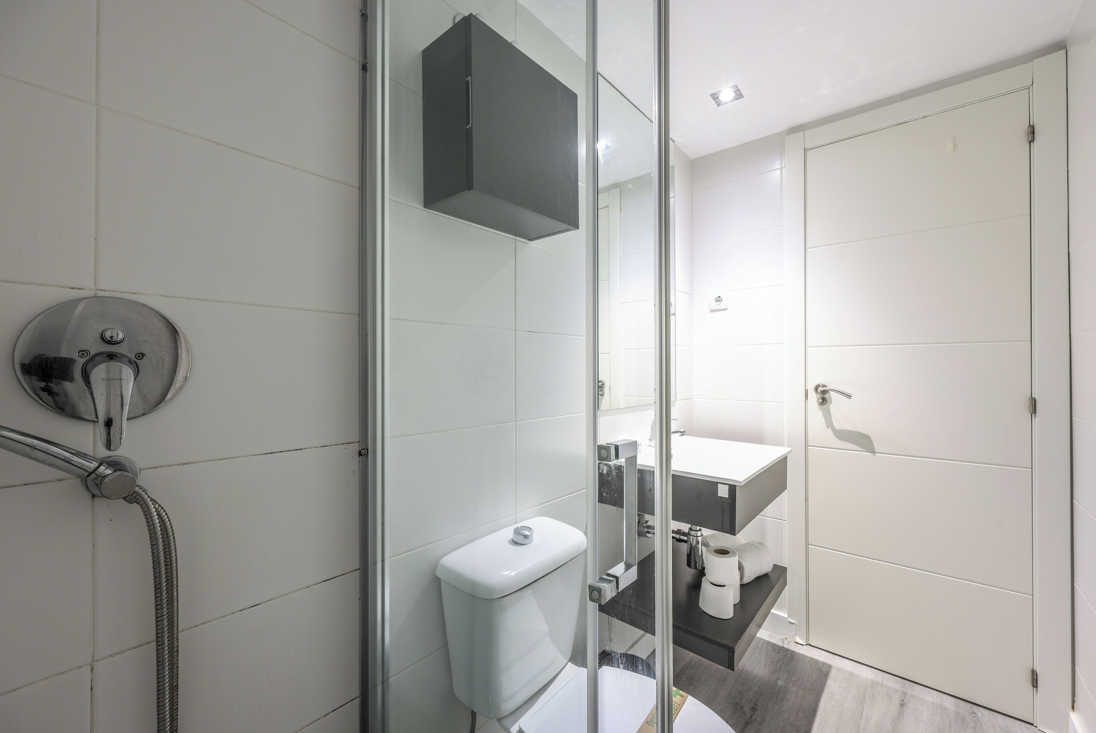 Un baño moderno con cabina de ducha de vidrio, inodoro y lavamanos.
