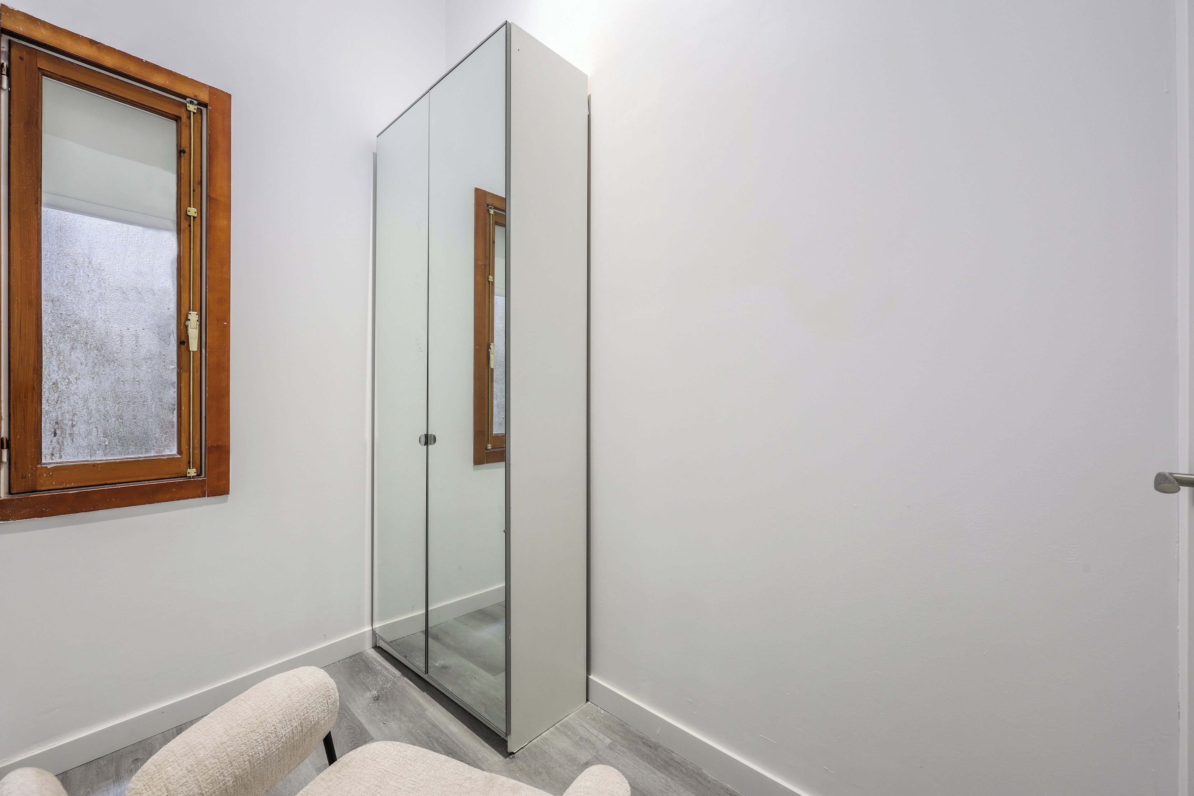 A room with a sliding glass door, a wooden-framed window, and a light-colored floor.